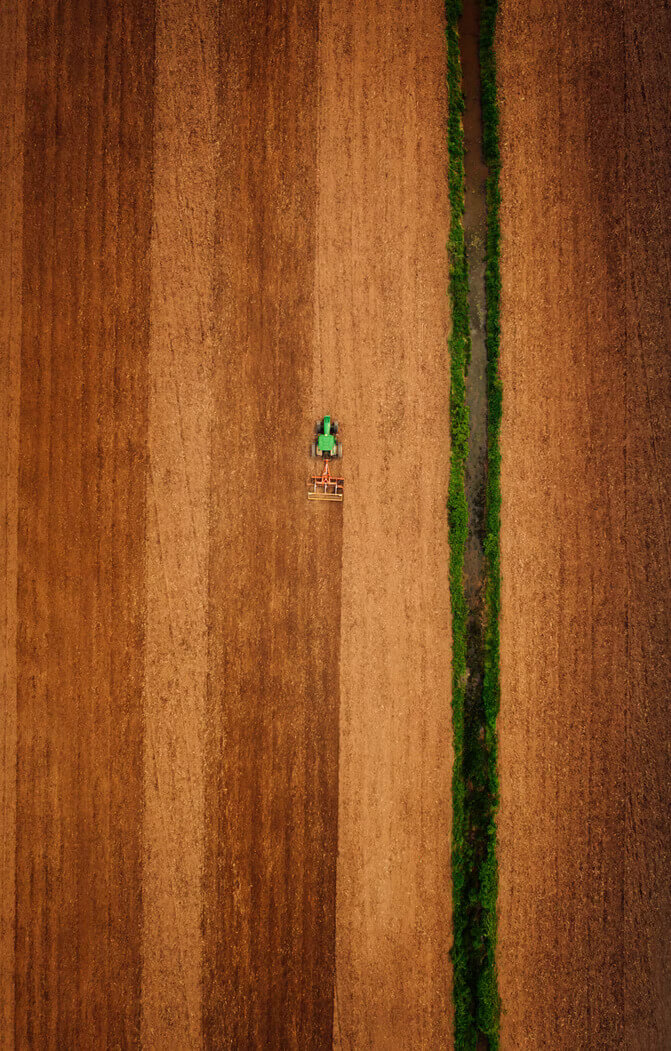 Aerial shot of a farmer sewing a field on a tractor