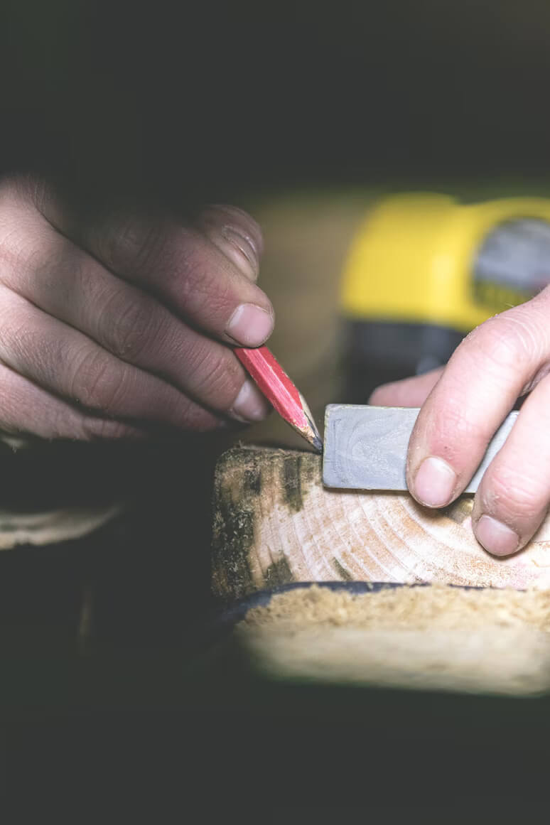 contractor marking a piece of wood using a pencil and ruler